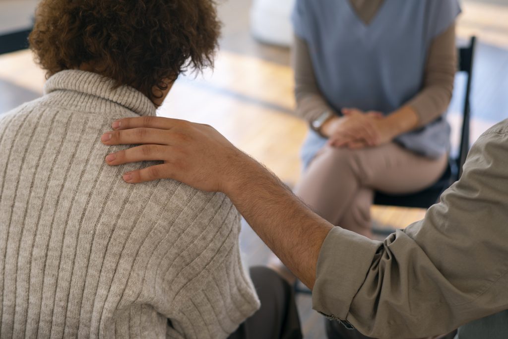 Supportive hand on a person’s shoulder during inner child work therapy session