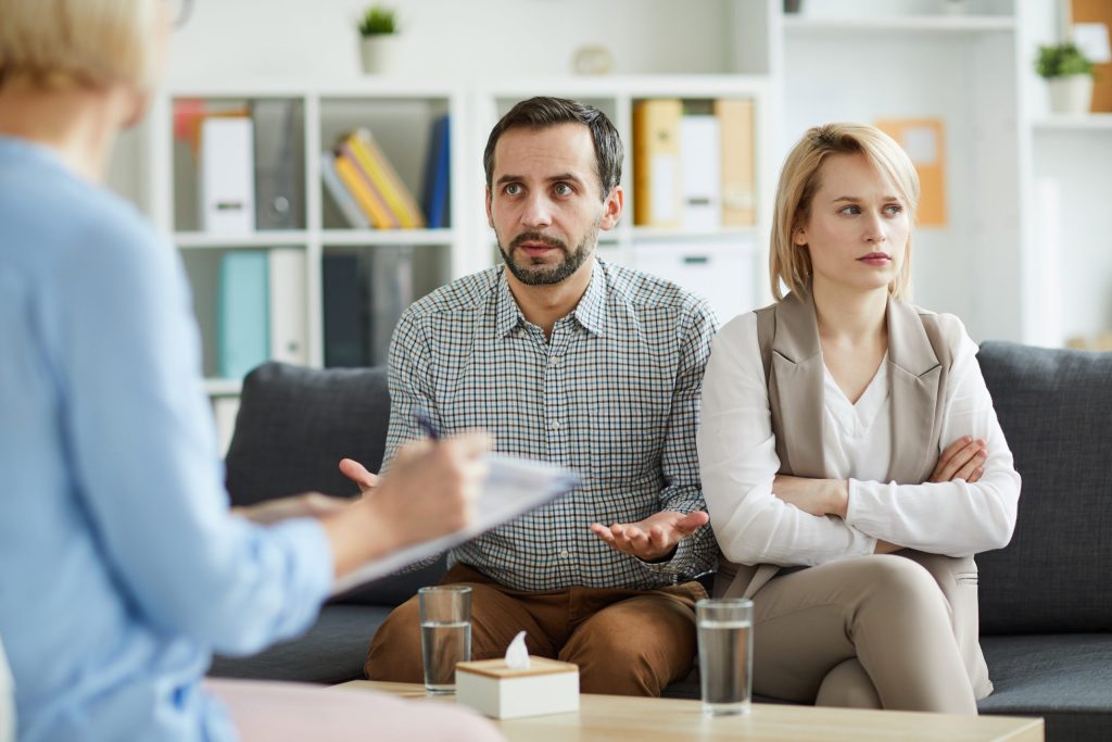 Couple in marriage counseling session with therapist discussing relationship challenges